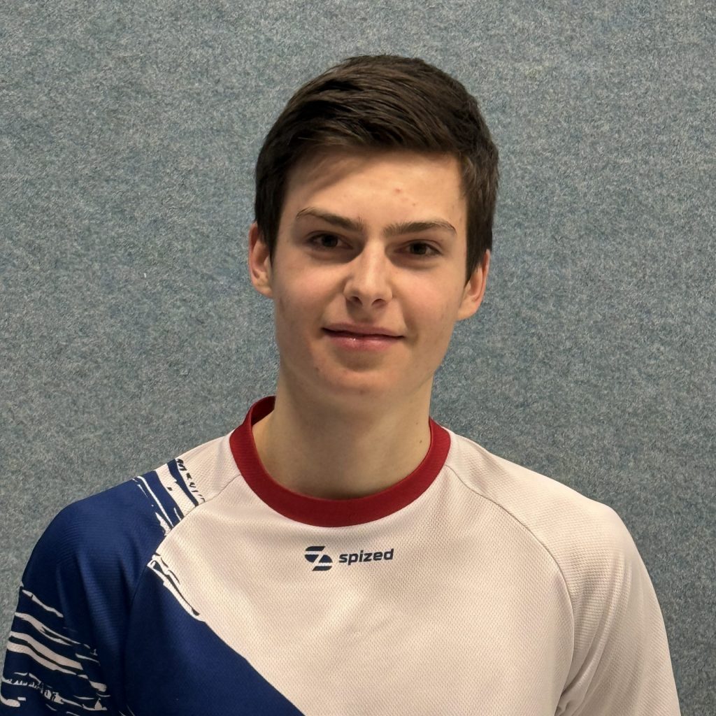 Sportler mit braunem Haar (Linus Haack) steht vor grauer Wand und trägt weißes Trikot mit blauem diagonalem Muster und rotem Kragen